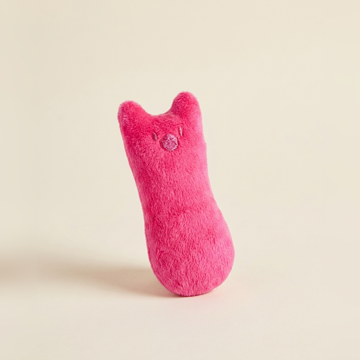 Pink plush catnip kicker cat toy, an elongated thumb shape with small ears