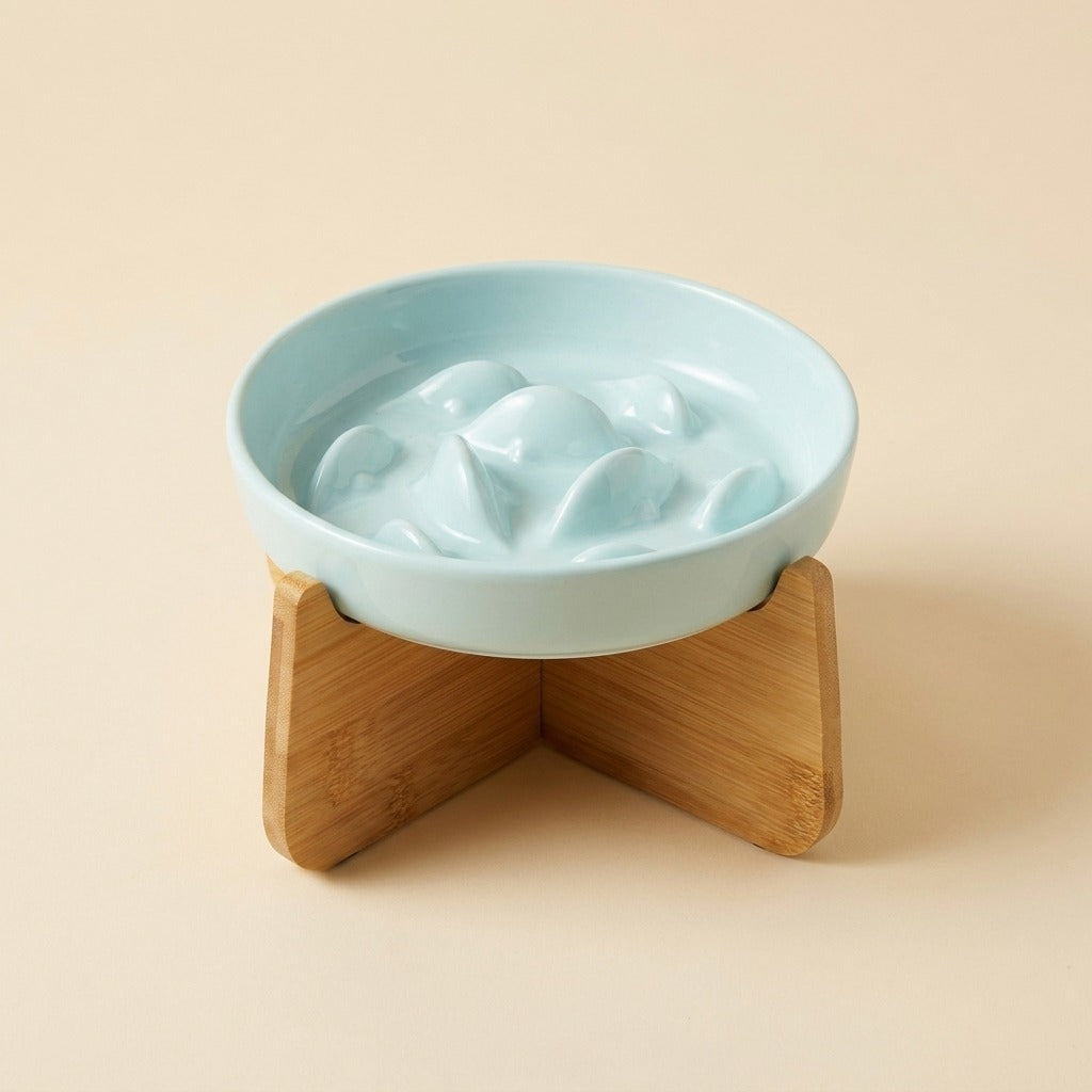 Ceramic Slow Feeder Cat Bowl in light blue on bamboo stand, studio shot