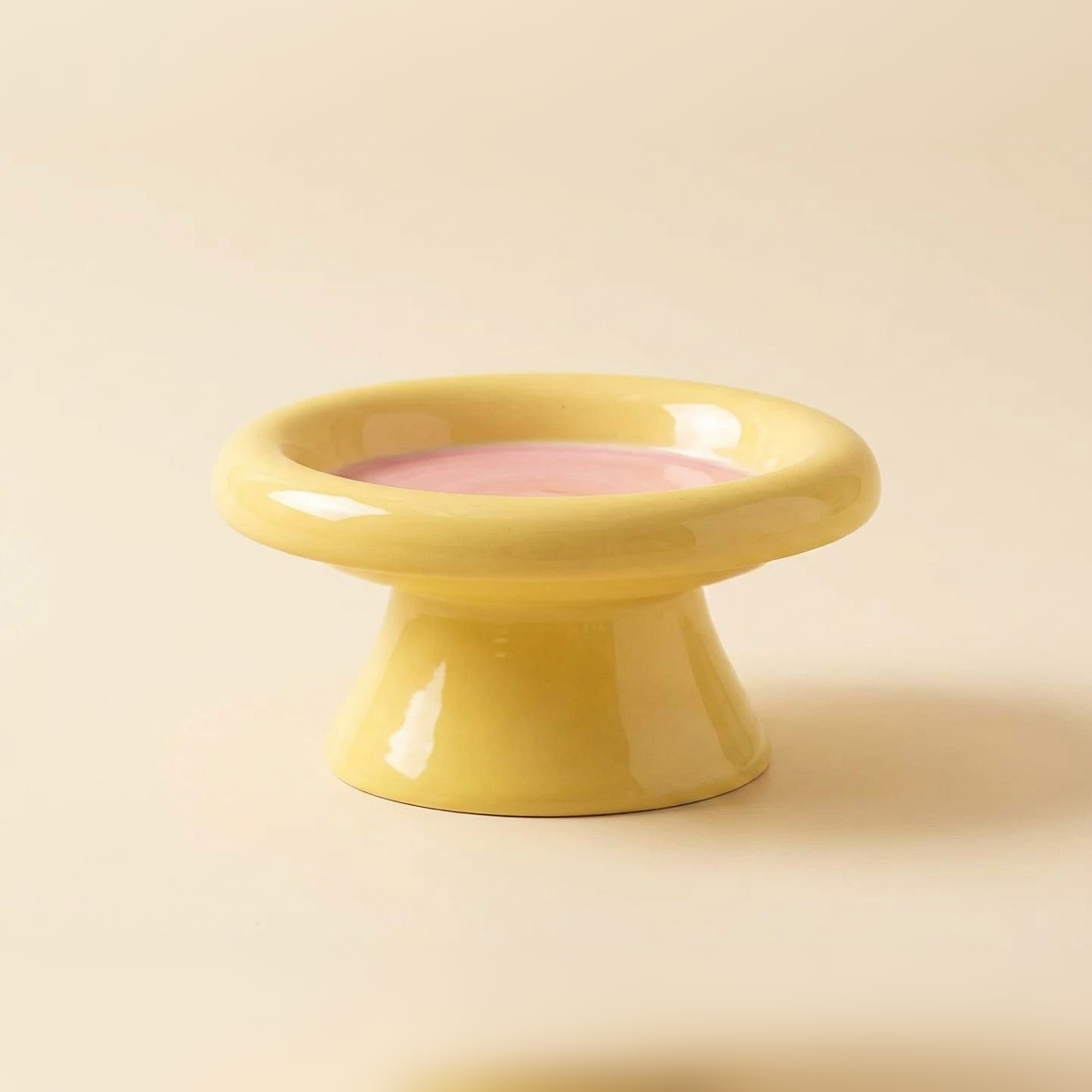 Wide pedestal cat bowl in yellow with a contrasting pink inner surface